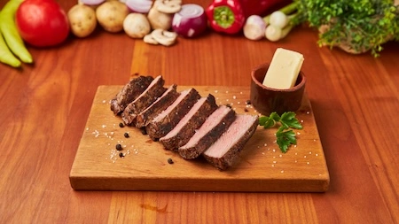 Juneći ramstek na žaru isečen na šnite, poslužen na drvenoj dasci sa puterom u Restoranu Gradska Beograd.