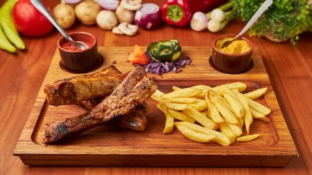 Marinirana svinjska rebra sa pomfritom i sosovima, poslužena na drvenoj dasci u Restoranu Gradska Beograd.